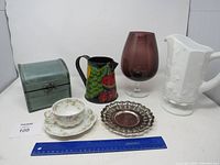 Photo showing all items in the lot including wooden box, ceramic pitcher, glass vase, cup and saucer, and metal tray with ruler for scale.