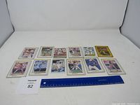 Lot of 11 vintage baseball cards laid out in two rows with a ruler for scale and lot number card 82.