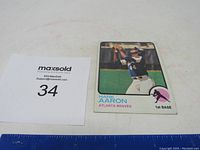 Photo of vintage Hank Aaron baseball card showing player catching a ball in blue and white Atlanta Braves uniform.