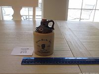 Front view of entire jug with ruler for size reference on table.