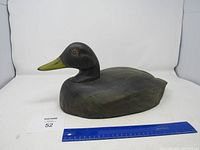 Full view of the wooden duck decoy with ruler showing size.