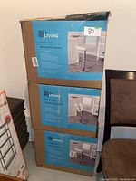 Three stacked unopened boxes of Living brand tufted bar stools with product info visible