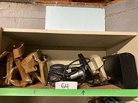 Overall view of shelf containing circular saw, sanding block, leather tool pouch, and black box.