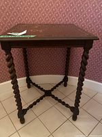 Full side angle view of the square wood accent table against wallpaper background.