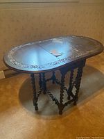 Table shown fully extended with both drop leaves raised, highlighting carved floral border and twisted spindle legs.