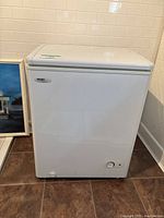 Full front view of white Danby Millennium chest freezer with brand logo and control knob visible.