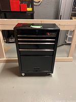 Front view of the black Excel rolling tool cabinet showing four drawers and caster wheels.
