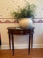 Full view of the console table with the faux plant on top, showing overall condition and setting.