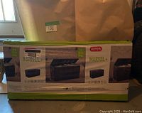Photo showing the boxed Keter Marvel+ outdoor storage bench 71 gallons capacity. Box graphics and product images visible.