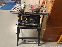 Front view of the Mastercraft 10 inch table saw with the integrated stand, power cord visible, table surface with metal grating and safety blade guard.