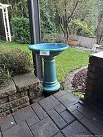 Full view of assembled bird bath placed outdoors on patio near garden.