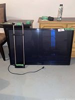 Samsung 50 inch flat screen TV front view with wall mount bracket leaning against it, showing dimensions label and power cord.