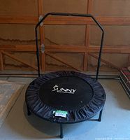 Front view of the Sunny Health & Fitness mini trampoline rebounder with handle in garage setting.