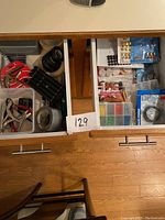 Two kitchen drawers filled with various tools, hardware and fastener kits in plastic organizers and packages.