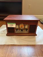 Front view of the wooden Victrola record player showing analog dial, control knobs, and speaker grills.