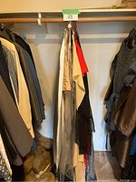 Dresses hanging on wooden rod in closet among other clothes showing variety and condition
