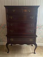 Front view showing six drawers with brass handles and cabriole legs in mahogany finish.