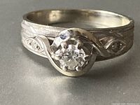 Front view showing central diamond and swirl-engraved band