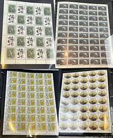 Four sheets of Canadian stamps displayed on black album page with bird, moon, map and fish designs