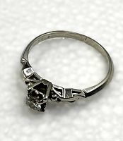 Angle view showing six-prong setting, filigree shoulders and round diamond solitaire.