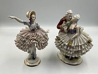 Two porcelain Dresden figurines together; one single female dancer and one dancing couple.