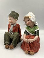 Front view of both Dutch boy and girl bisque figurines seated together