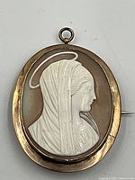 Front view of the antique Madonna cameo brooch/pendant showing the white cameo relief and gold frame.