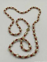 Full view of the coral and pearl necklace laid out in a roughly heart shape showing length and bead pattern.