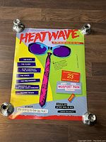 Full front view of the poster secured by candle holders on a wooden floor