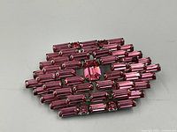 Front view of Jay Flex sterling silver brooch set with rectangular pink stones in a diamond shape.