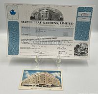 Photo showing the Maple Leaf Gardens Limited share certificate displayed on an easel alongside the collector postcard depicting the building.