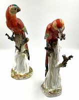 Two Meissen porcelain parrot figurines side by side on white background