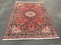 Full view of rug laid flat on pavement showing overall pattern and fringe