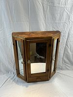 Front view of pine medicine cabinet showcasing three mirrored doors and vintage metal knobs.