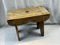 Front view of the rustic pine stool showing the full stool with legs and top surface.