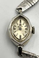 Close-up of watch face showing Omega logo, hexagonal case shape, baton markers and winding crown