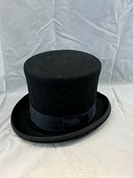 Front view of the vintage black felt top hat against white backdrop.