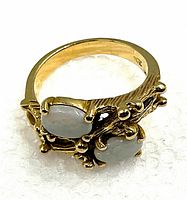 Front angled view of ring showing two opal stones and textured gold band