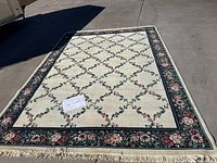 Full view showing carpet size and floral pattern with cream center and dark green floral border