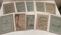 Ten vintage opera librettos arranged on a flat surface, showing front covers with detailed period artwork and typography typical of late 19th to early 20th century.