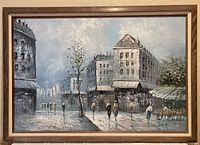 Full view of the framed cityscape oil painting showing the entire urban scene with multiple buildings, trees, and pedestrians on a rainy or wet street.