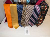 Close-up view of eight assorted silk ties showing a range of colors and patterns including solid, polka dots, geometric, and striped.