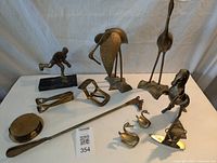 Photo showing all items including coasters, vintage buckle, horse statues, birds, horse shoe horn, hockey statue, and tongs arranged on table.