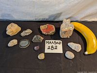 Overview of all 11 pieces including petrified wood, polished stones, quartz, agate slice, and other stones with a banana for scale.