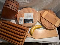 Photo showing the 7-piece set including multiple wooden cutting boards, knife block, and bread slicer rack with a banana for size reference.