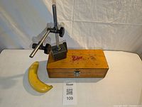 Eclipse magnetic gauge stand with extension arm placed on top of a wooden case, alongside a banana for scale.