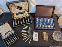 Full view of all flatware sets arranged on a surface, including boxes and the small crystal bowl. Banana used for scale is visible but not part of lot.
