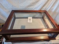 Top angled view of wooden glass display cabinet showing wood frame and glass top