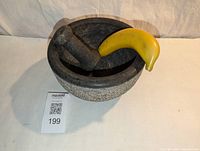 Stone mortar and pestle set with banana for scale showing textured exterior.