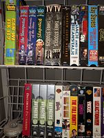 Two rows of VHS tapes showing a mix of classic TV series, movies, and cartoons including Bob the Builder, The Avengers series, and The Three Stooges.